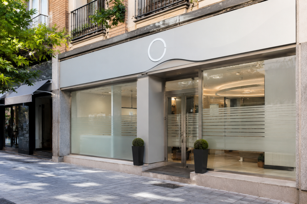 Entrada de clínica moderna con rótulo exterior y vinilos discretos en cristales